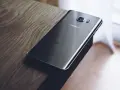 Czarny Samsung leży na drewnianym blacie. Chcesz wiedzieć, jak zresetować telefon Samsung?