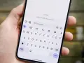 Dłoń trzyma smartfon z otwartą klawiaturą. Widoczny komunikat "RCS chat with Judy" sugeruje, jak włączyć czat RCS.