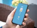 Dłoń trzyma smartfon z wyświetloną grafiką porównującą tradycyjną kartę SIM z technologią eSIM.