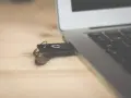 Pendrive z systemem Windows 10 bootable usb podłączony do laptopa na drewnianym biurku.