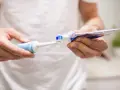 Przygotowanie do mycia zębów szczoteczką soniczną: nakładanie pasty na główkę.