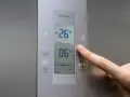 Palec naciska przycisk "super" na panelu lodówki no frost. Wyświetlacz pokazuje -26°C i 06°C.