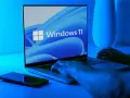 Ręce na klawiaturze laptopa z logo Windows 11. Dowiedz się, jak wejść do BIOS-u Windows 11, aby dostosować ustawienia.