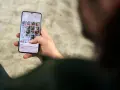 Osoba przegląda zdjęcia na telefonie, zastanawiając się, jak usunąć aplikacje z telefonu, by zwolnić miejsce.