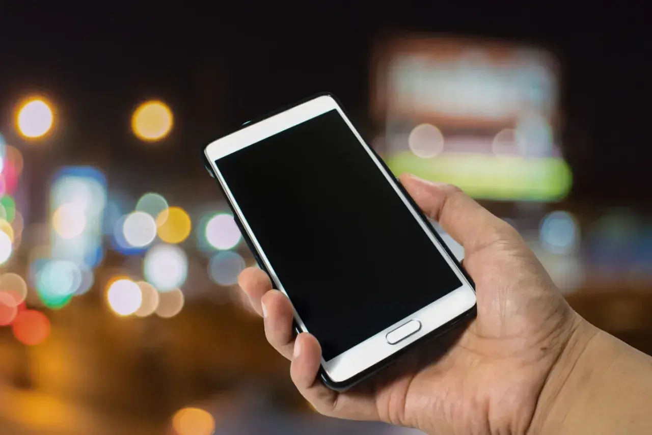 Dłoń trzyma smartfon Samsung. Zastanawiasz się, jak wyłączyć telefon Samsung bez dotyku? Oto rozwiązanie.