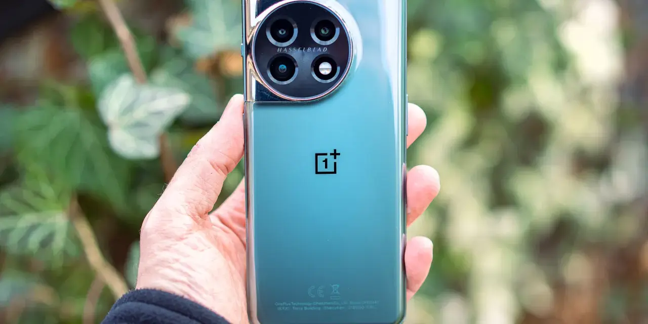 Dłoń trzyma zielony telefon z okrągłym aparatem Hasselblad.