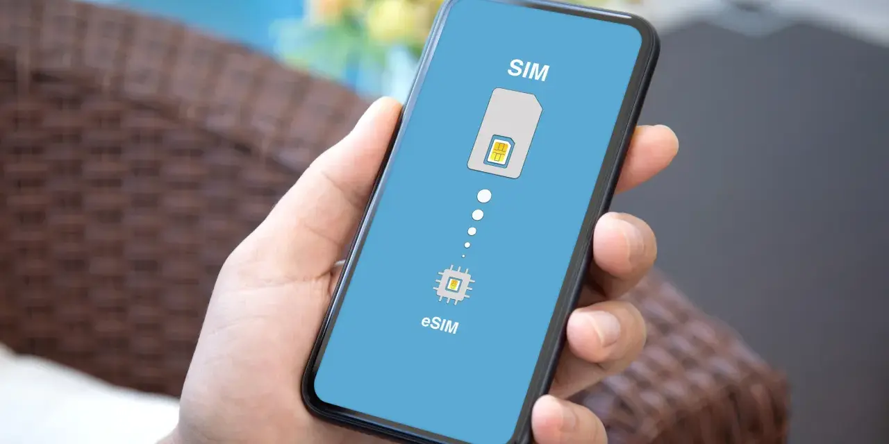 Dłoń trzyma smartfon z wyświetloną grafiką porównującą tradycyjną kartę SIM z technologią eSIM.