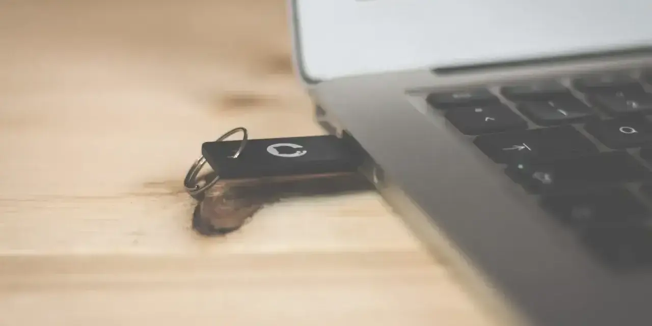 Pendrive z systemem Windows 10 bootable usb podłączony do laptopa na drewnianym biurku.