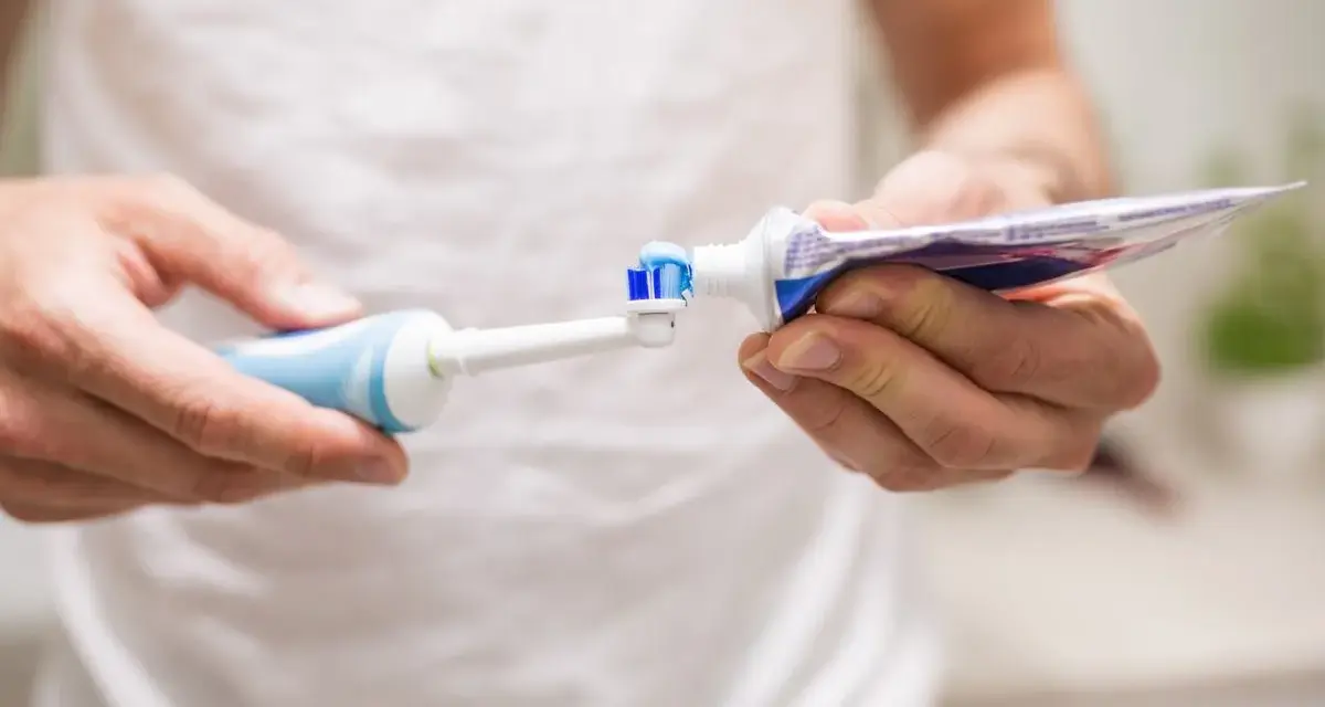 Przygotowanie do mycia zębów szczoteczką soniczną: nakładanie pasty na główkę.