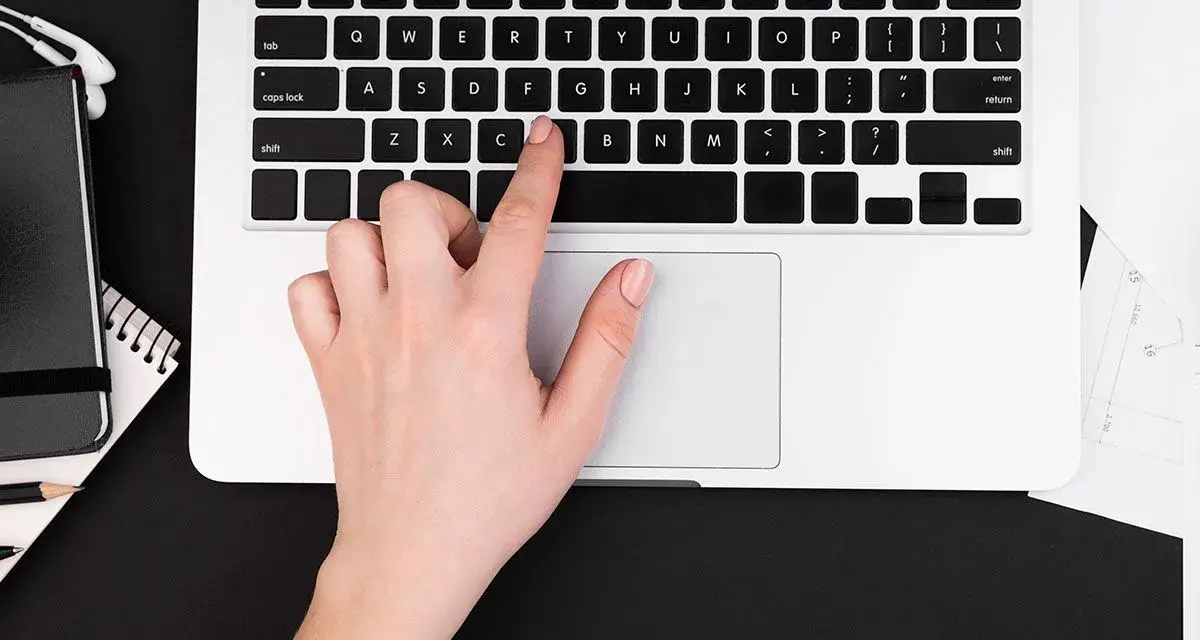 Dłoń naciska klawisz "C" na klawiaturze laptopa, co może być przyczyną, dlaczego nie działa klawiatura w laptopie.