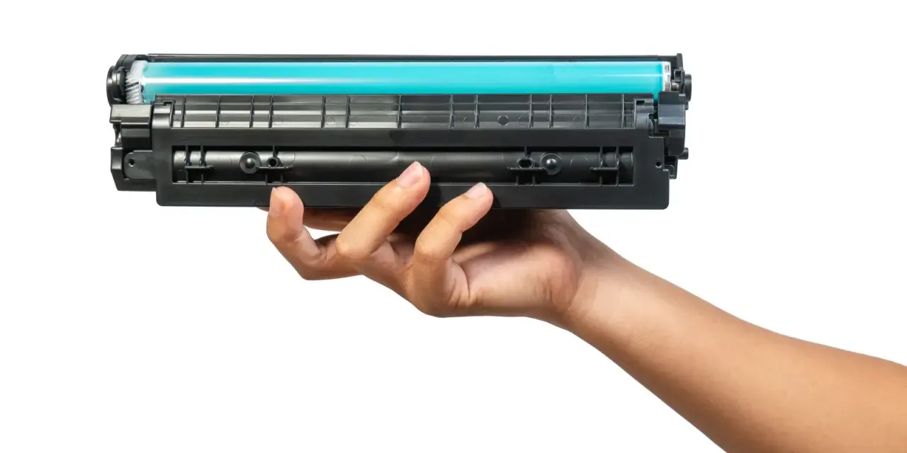 Dłoń trzymająca toner do drukarki HP. Dowiedz się, jak wymienić tusz w drukarce HP, aby cieszyć się wydrukami.