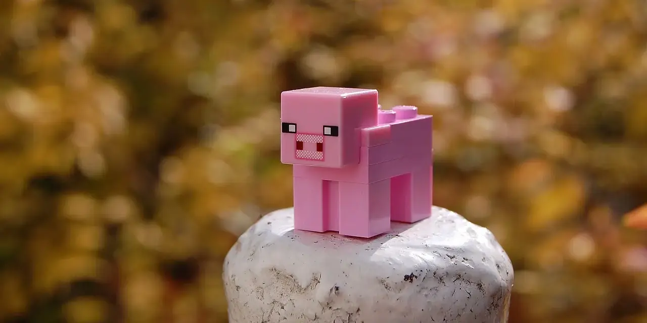Różowa świnka z klocków Minecraft na białym postumencie. Może to być inspiracja do najlepszych modów do Minecraft, które dodają nowe zwierzęta.