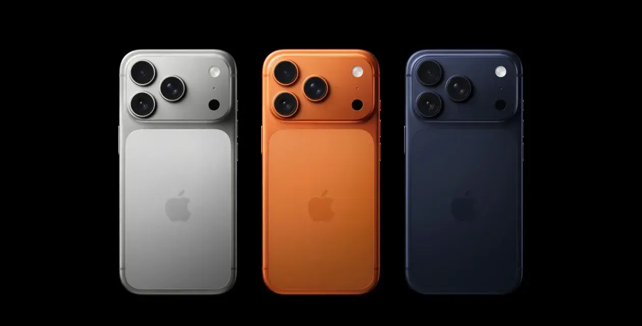 Trzy telefony iPhone w kolorach srebrnym, pomarańczowym i granatowym, z potrójnymi aparatami. Wyglądają jak przyszłe modele, może nawet iPhone 18.