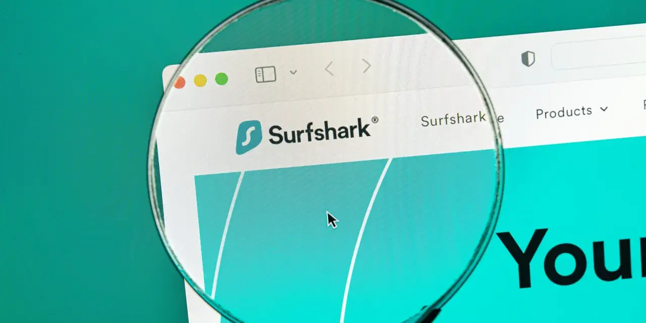 Lupa w telefonie powiększa logo Surfshark i fragment strony internetowej.