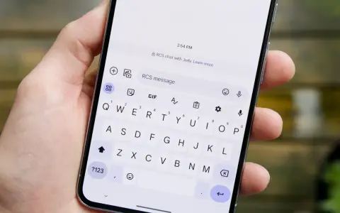 Dłoń trzyma smartfon z otwartą klawiaturą. Widoczny komunikat "RCS chat with Judy" sugeruje, jak włączyć czat RCS.
