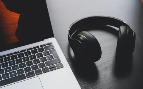 Słuchawki leżą obok laptopa. Może to być sygnał, że występuje brak dźwięku w laptopie i potrzebne są słuchawki do słuchania.