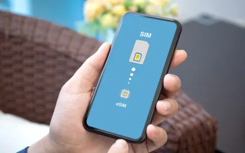 Dłoń trzyma smartfon z wyświetloną grafiką porównującą tradycyjną kartę SIM z technologią eSIM.