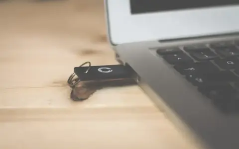 Pendrive z systemem Windows 10 bootable usb podłączony do laptopa na drewnianym biurku.