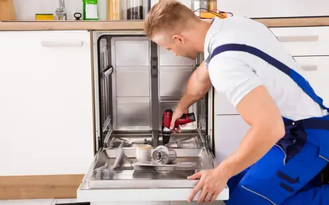 Fachowiec dokonuje montażu frontu do zmywarki, używając wiertarko-wkrętarki.
