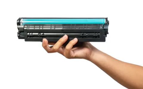 Dłoń trzymająca toner do drukarki HP. Dowiedz się, jak wymienić tusz w drukarce HP, aby cieszyć się wydrukami.