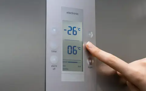 Palec naciska przycisk "super" na panelu lodówki no frost. Wyświetlacz pokazuje -26°C i 06°C.