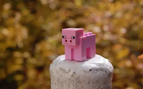 Różowa świnka z klocków Minecraft na białym postumencie. Może to być inspiracja do najlepszych modów do Minecraft, które dodają nowe zwierzęta.