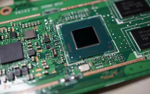 Zbliżenie na zieloną płytę główną laptopa z widocznym procesorem, gotowym do wymiany.