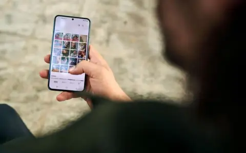 Osoba przegląda zdjęcia na telefonie, zastanawiając się, jak usunąć aplikacje z telefonu, by zwolnić miejsce.