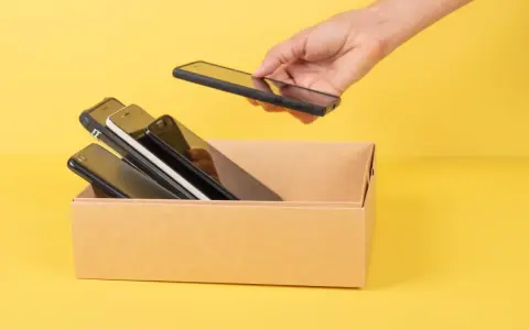 Ręka wkłada do kartonu kilka telefonów. Zastanawiam się, jaki mam model telefonu, bo wszystkie wyglądają podobnie.