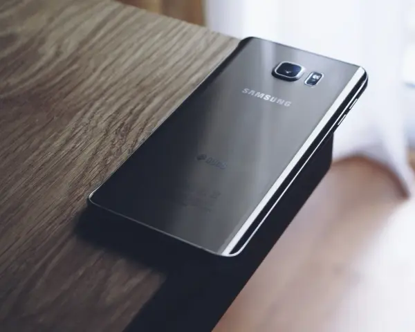 Czarny Samsung leży na drewnianym blacie. Chcesz wiedzieć, jak zresetować telefon Samsung?