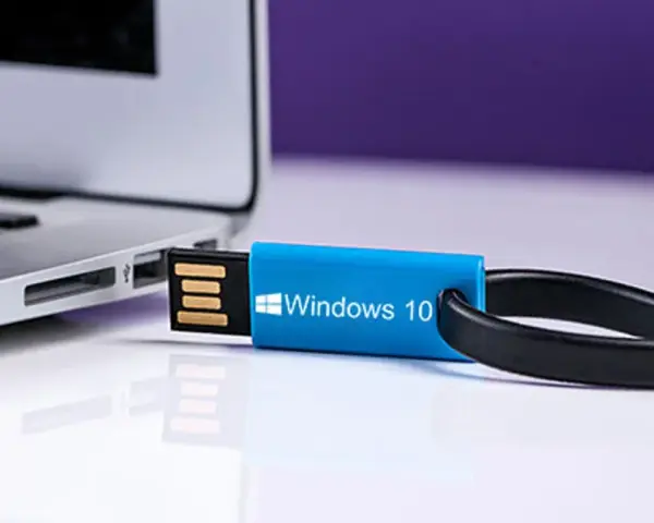 Niebieski pendrive z napisem "Windows 10" podłączony do laptopa. Idealny do nauki, jak zrobic format komputera win 10.