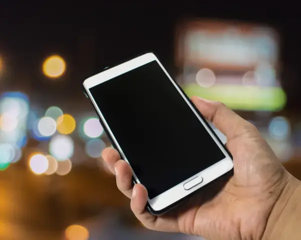 Dłoń trzyma smartfon Samsung. Zastanawiasz się, jak wyłączyć telefon Samsung bez dotyku? Oto rozwiązanie.