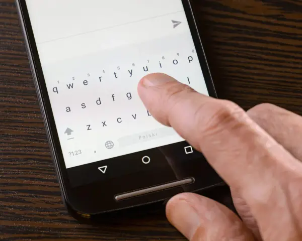 Palec naciska klawisz "Polski" na klawiaturze telefonu, aby włączyć polskie znaki w SMS.