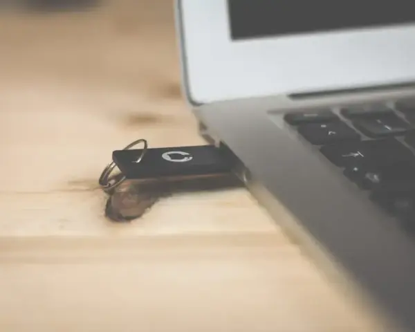 Pendrive z systemem Windows 10 bootable usb podłączony do laptopa na drewnianym biurku.