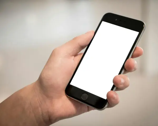 Dłoń trzyma smartfon z pustym ekranem. Cisza, brak id dzwoniącego.