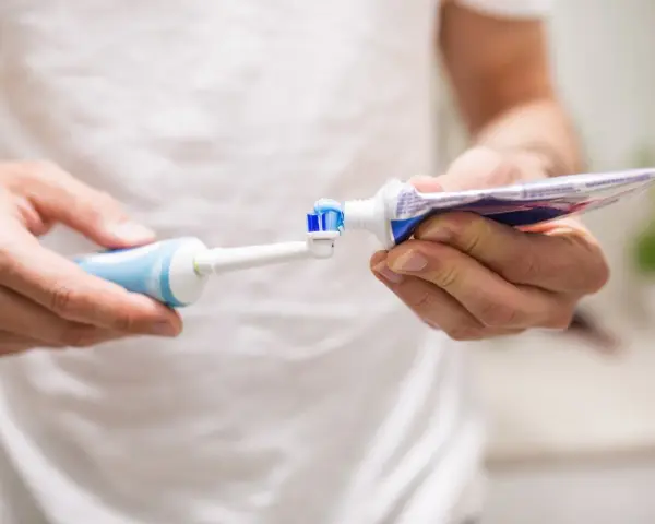 Przygotowanie do mycia zębów szczoteczką soniczną: nakładanie pasty na główkę.