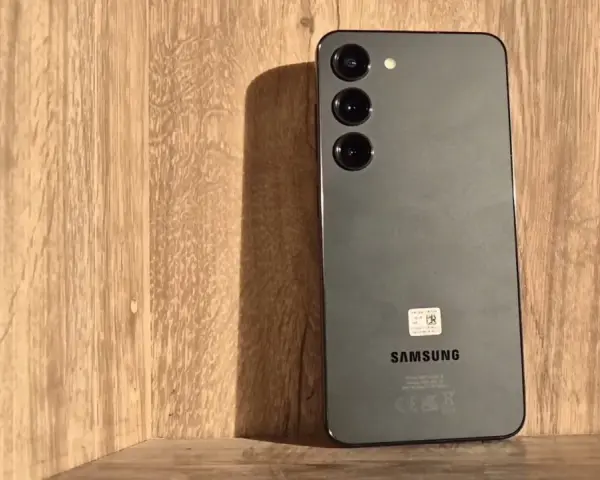 Szary Samsung S23 z trzema obiektywami aparatu na drewnianym tle. Długo działająca bateria pozwoli Ci cieszyć się nim przez cały dzień.