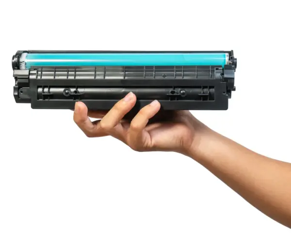 Dłoń trzymająca toner do drukarki HP. Dowiedz się, jak wymienić tusz w drukarce HP, aby cieszyć się wydrukami.