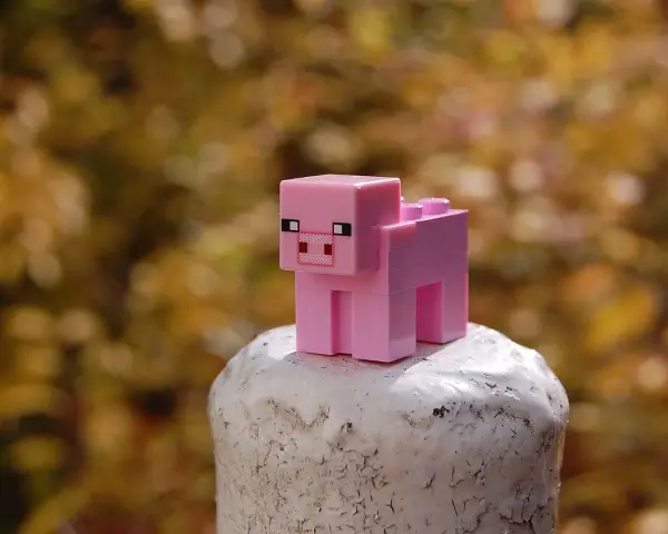 Różowa świnka z klocków Minecraft na białym postumencie. Może to być inspiracja do najlepszych modów do Minecraft, które dodają nowe zwierzęta.