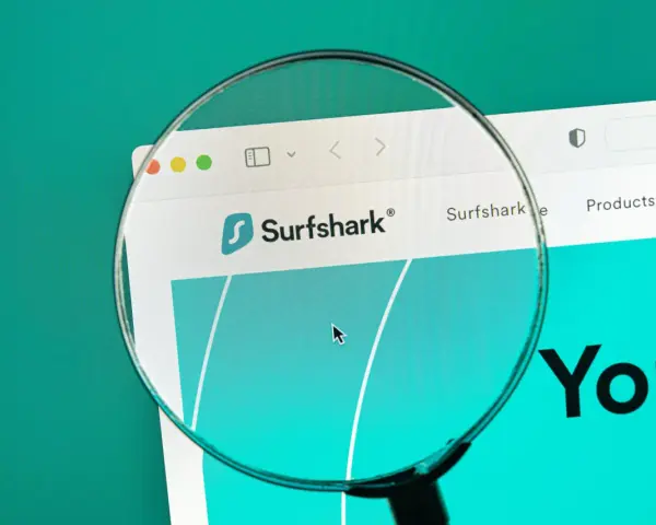 Lupa w telefonie powiększa logo Surfshark i fragment strony internetowej.