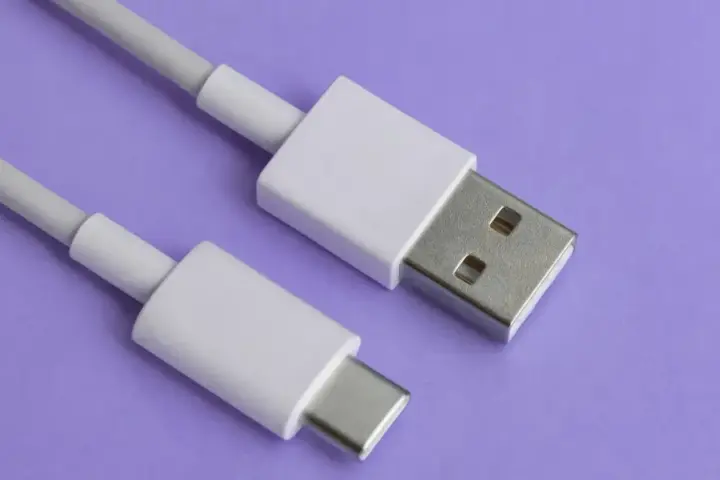 Biały kabel z wtyczkami USB-A i USB typu C na fioletowym tle.