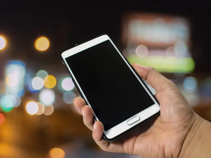 Dłoń trzyma smartfon Samsung. Zastanawiasz się, jak wyłączyć telefon Samsung bez dotyku? Oto rozwiązanie.