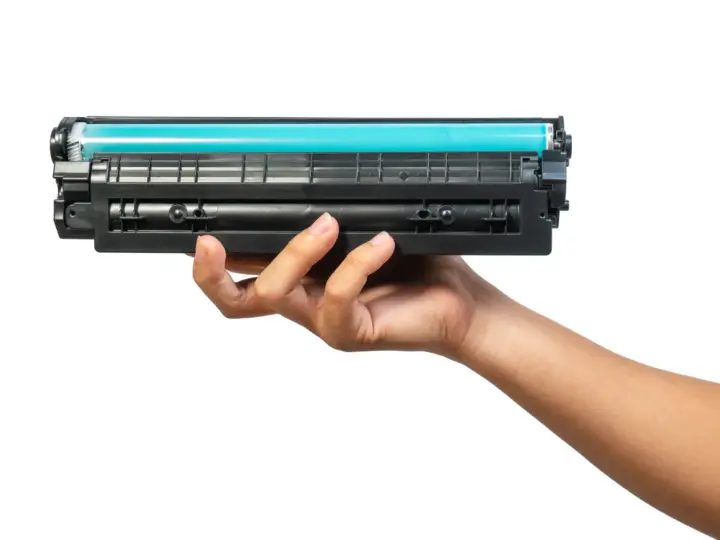 Dłoń trzymająca toner do drukarki HP. Dowiedz się, jak wymienić tusz w drukarce HP, aby cieszyć się wydrukami.