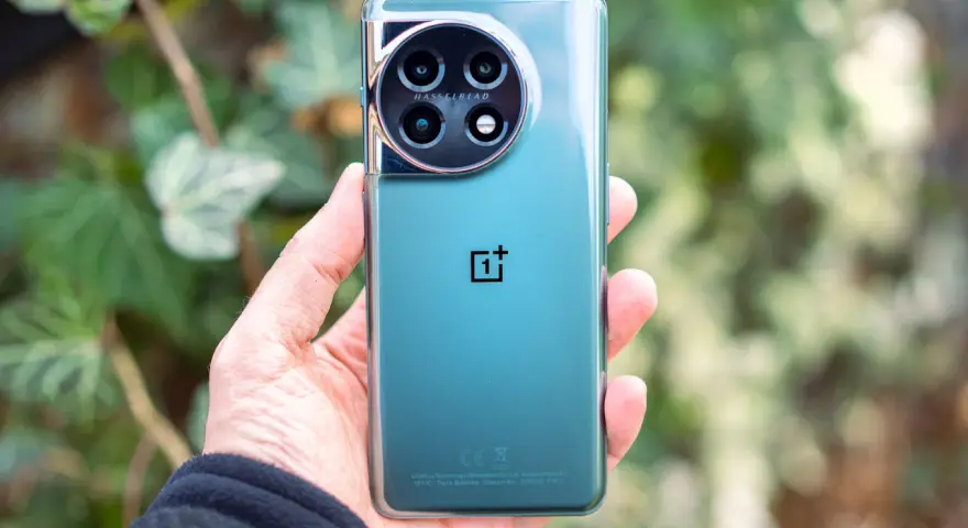 Dłoń trzyma zielony telefon z okrągłym aparatem Hasselblad.