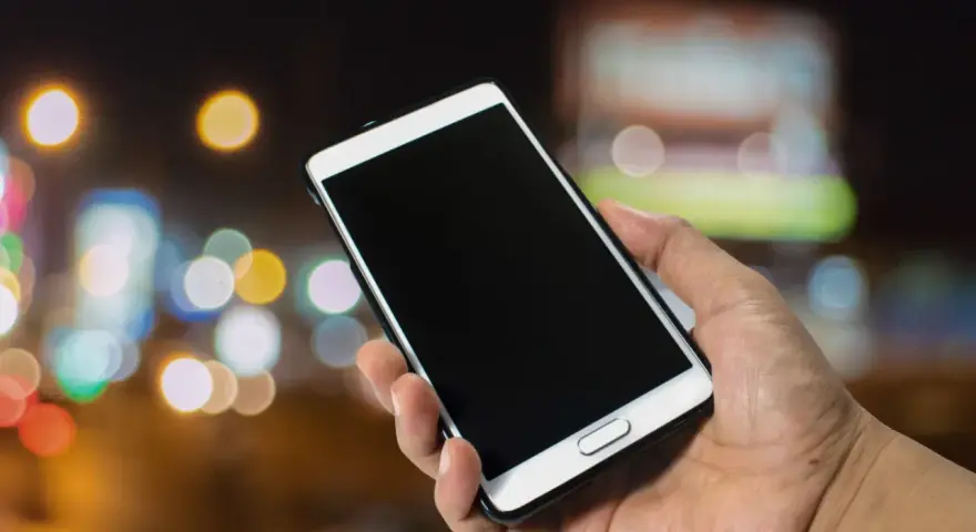 Dłoń trzyma smartfon Samsung. Zastanawiasz się, jak wyłączyć telefon Samsung bez dotyku? Oto rozwiązanie.