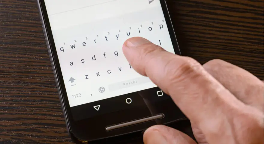 Palec naciska klawisz "Polski" na klawiaturze telefonu, aby włączyć polskie znaki w SMS.