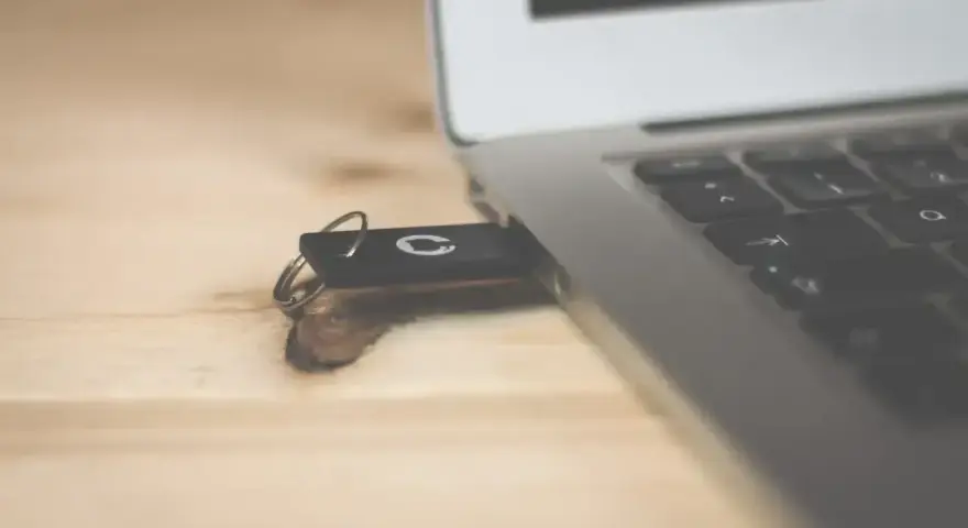 Pendrive z systemem Windows 10 bootable usb podłączony do laptopa na drewnianym biurku.