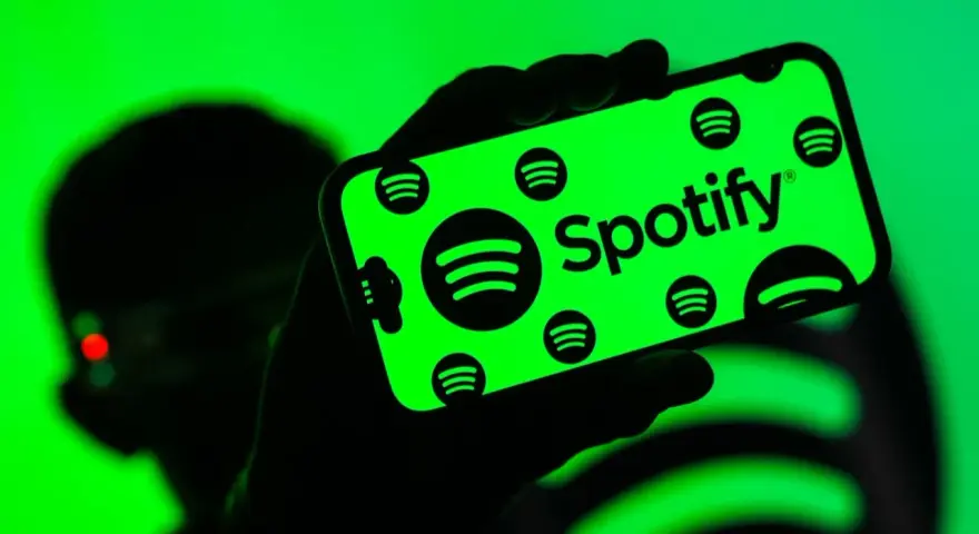 Dłoń trzyma smartfon z zielonym ekranem, na którym widnieje logo Spotify. Użytkownik cieszy się doskonałą spotify jakość dźwięku.