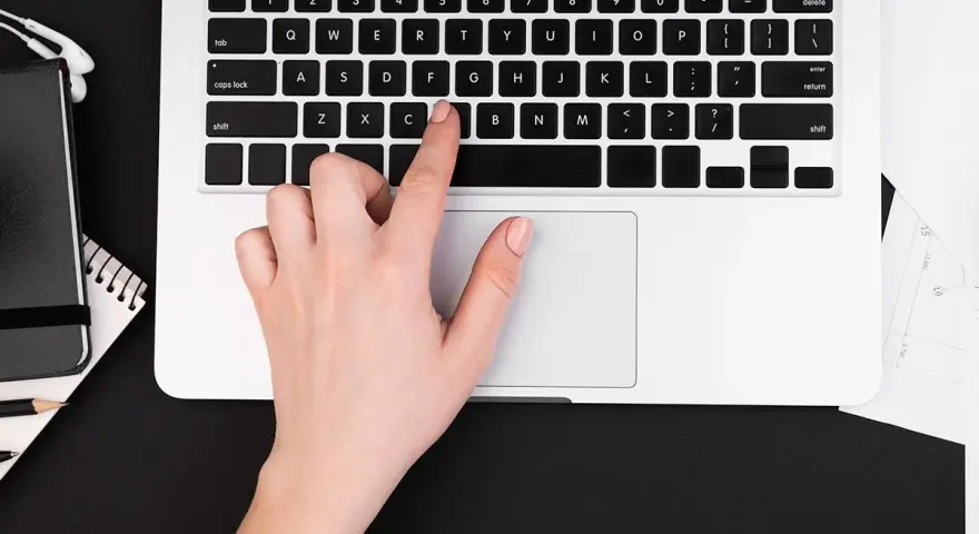 Dłoń naciska klawisz "C" na klawiaturze laptopa, co może być przyczyną, dlaczego nie działa klawiatura w laptopie.