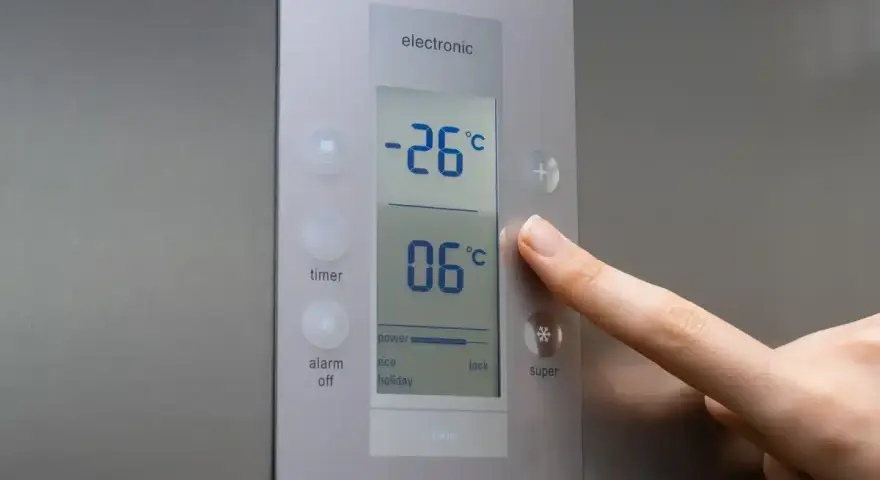 Palec naciska przycisk "super" na panelu lodówki no frost. Wyświetlacz pokazuje -26°C i 06°C.